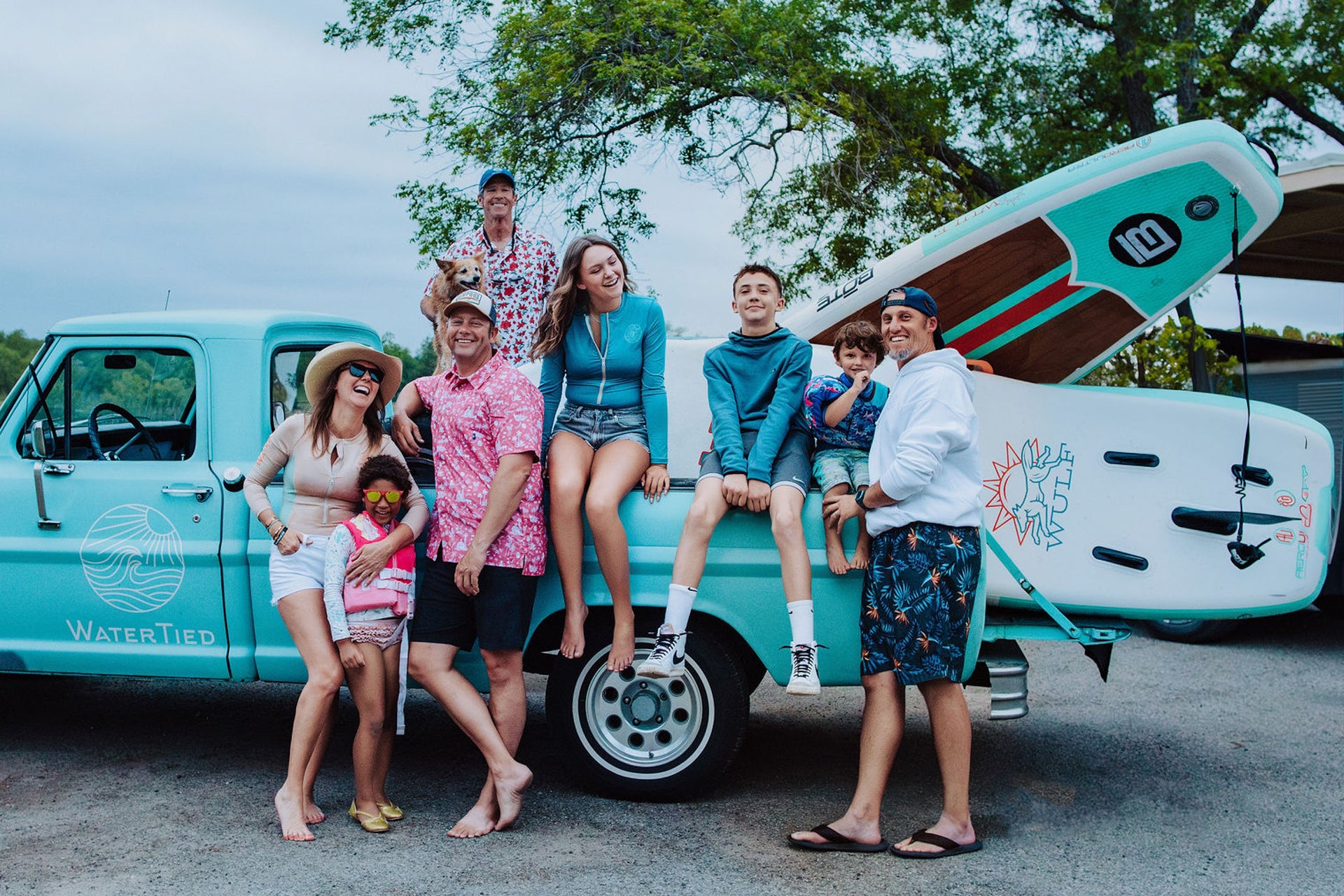 Family posing in front of a vintage truck with paddleboards on a road trip in southern Hill Country.