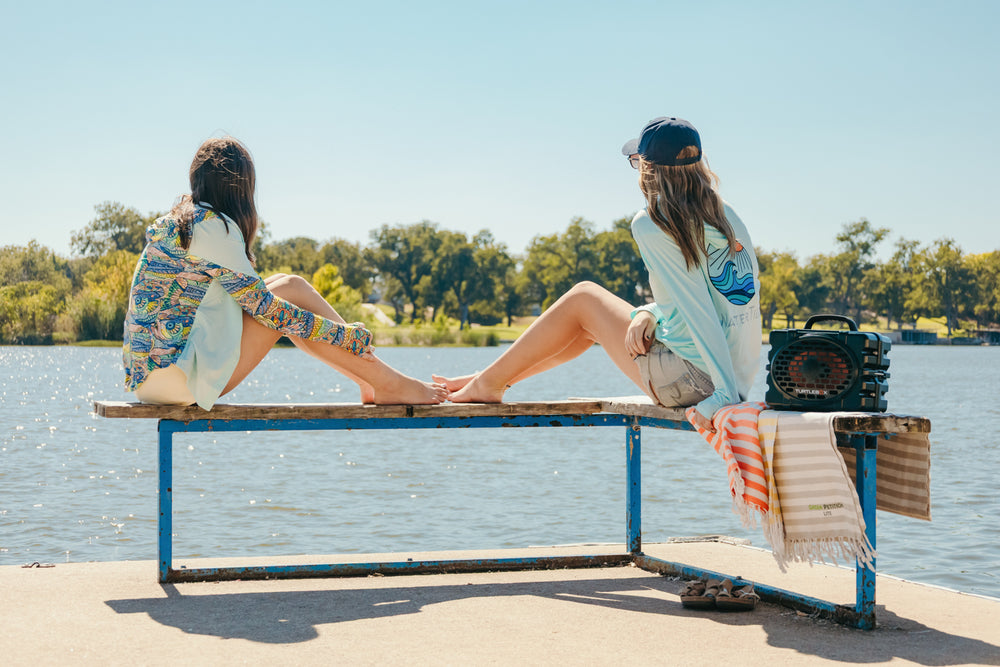 Two people sitting on a bench by a lake in Marble Falls with a clear blue sky.