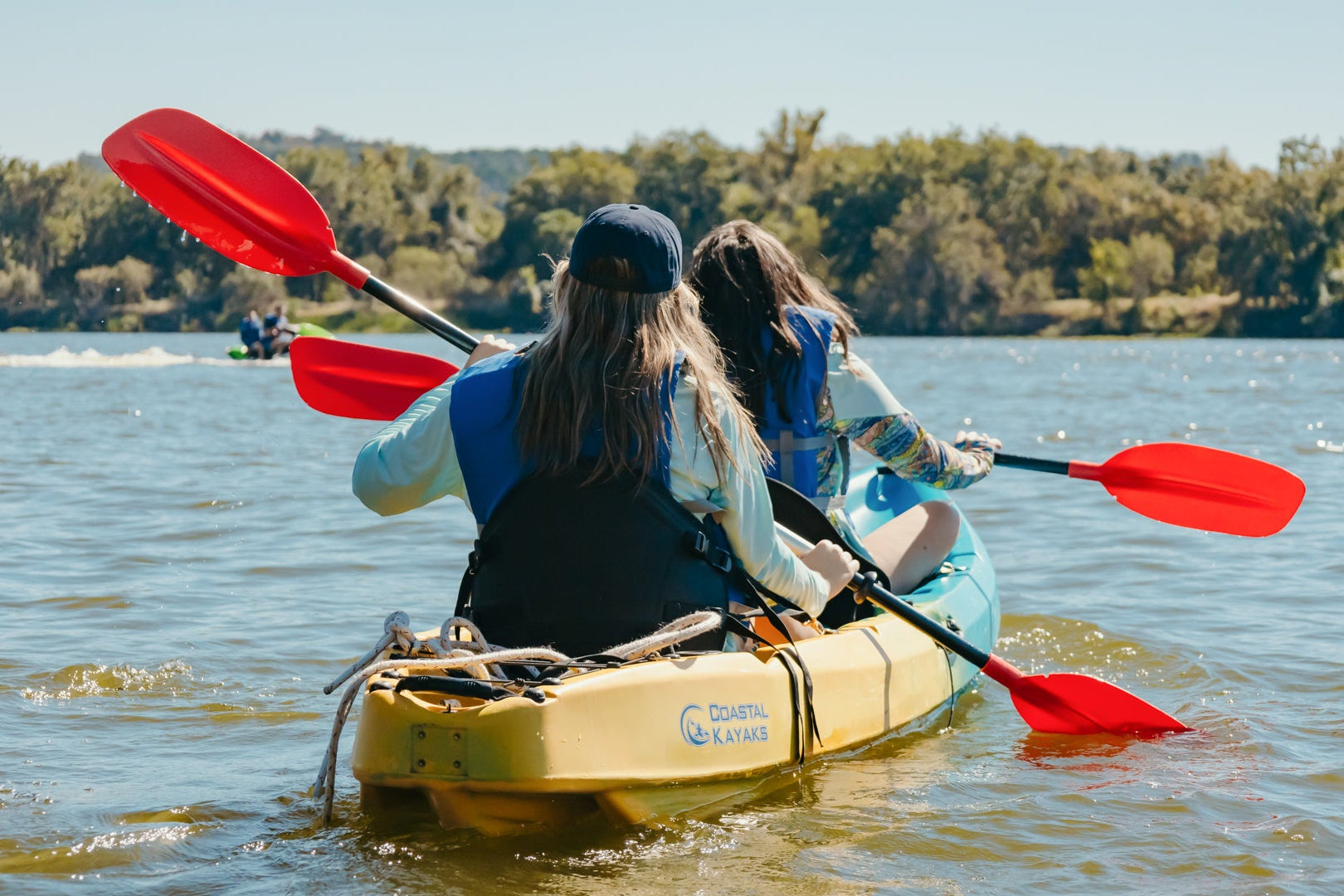 Two people kayaking on a lake in Texas Hill Country with a scenic background
