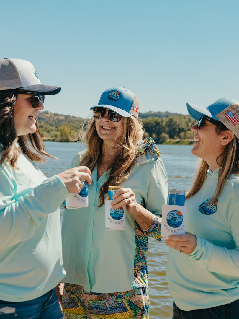 Three women by a lake in central Texas, holding WaterTied bottles with a blue sky and water background.